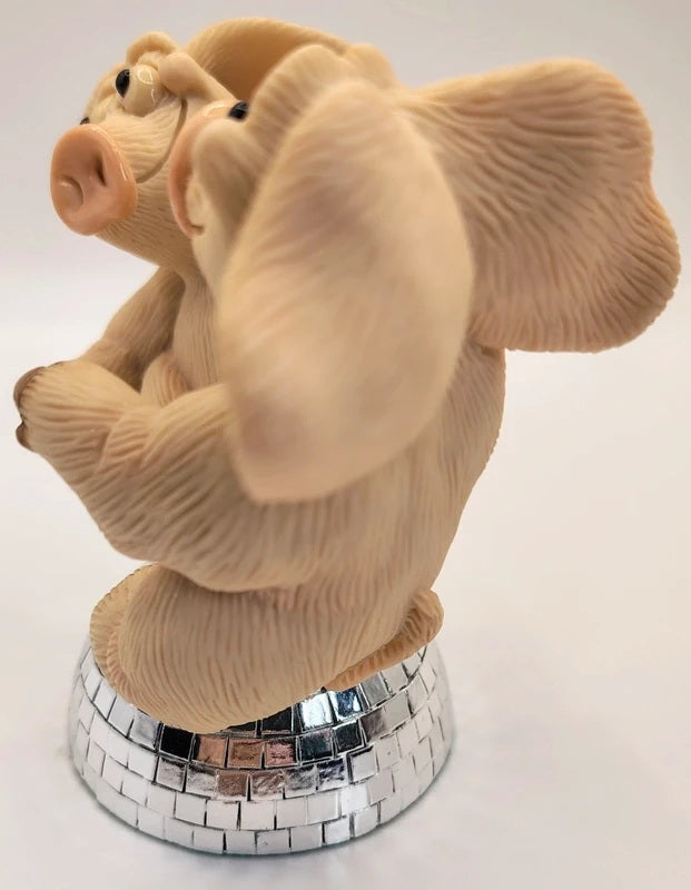 A beige sculpted pig figurine with textured fur, posed sitting on a mirrored silver disco-ball base against a plain white background.