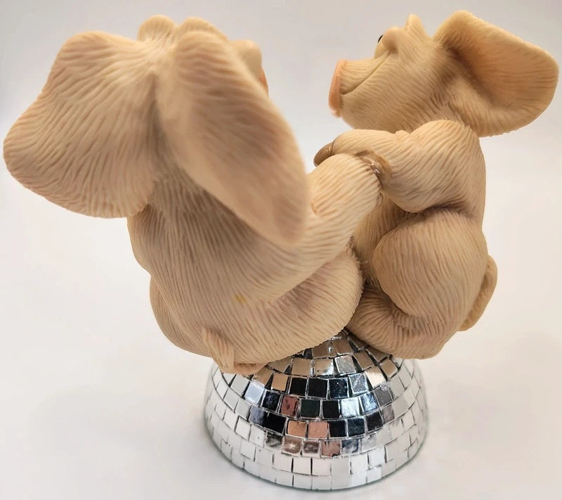 A decorative figurine of two dancing pigs facing away from the camera, mounted on a mirrored disco ball base against a plain white background.