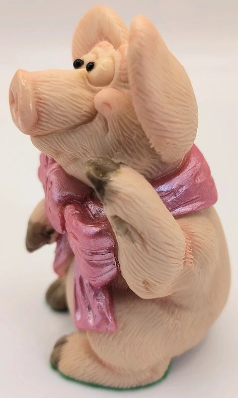 A pig figurine with a pink bow, standing on a white background.