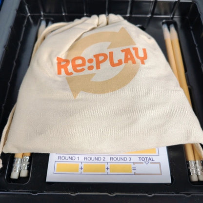 Re:Play branded drawstring bag with pencils and a scoreboard in a black container.