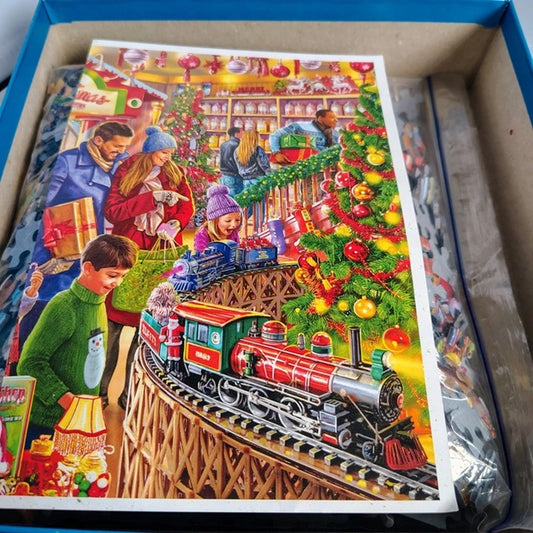 Colorful Christmas-themed puzzle with a train and people around a tree in a box.