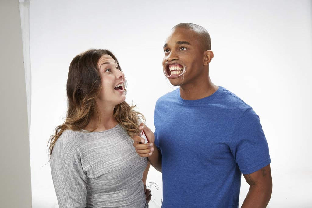 Two people laughing together on a plain background