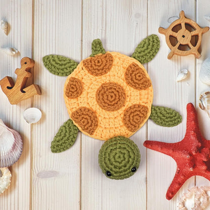 Crocheted turtle toy on a wooden surface with decorative items
