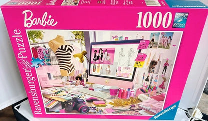 Barbie-themed Ravensburger jigsaw puzzle box with images of dolls and accessories on a pink background.