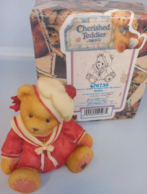 Cherished Teddies bear in red outfit with packaging in the background