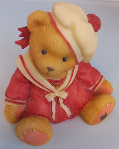 Teddy bear figurine in a red outfit with a white hat on a white background