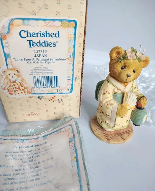 Cherished Teddies Japan 'Love Fans A Beautiful Friendship' girl with fan figurine shown next to its original packaging box and certificate of authenticity.