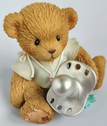 Cherished Teddies Babys Christening Baby Boy Figurine teddy bear holding a large silver pacifier dummy on a light gray background.
