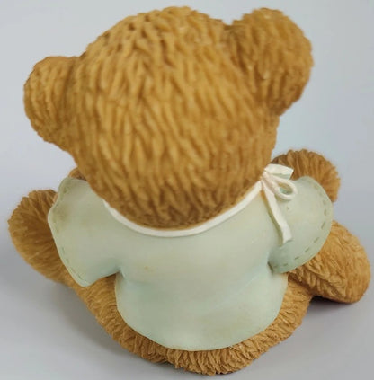 Brown teddy bear with a green shirt on a white background
