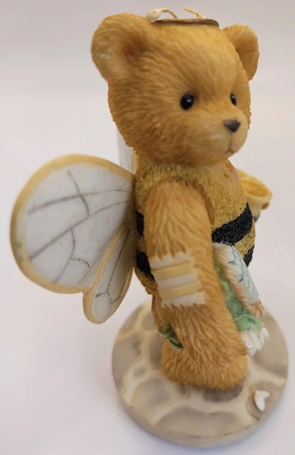 Teddy bear with bee wings and a flower on a white background