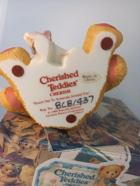 Cherished Teddies teddy bear ornament with visible branding on a surface with other similar items.
