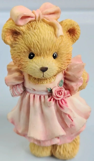 Cherished Teddies Child of Love teddy bear wearing a pink dress with a bow on a light gray background. Our Cherished Family. 624845.