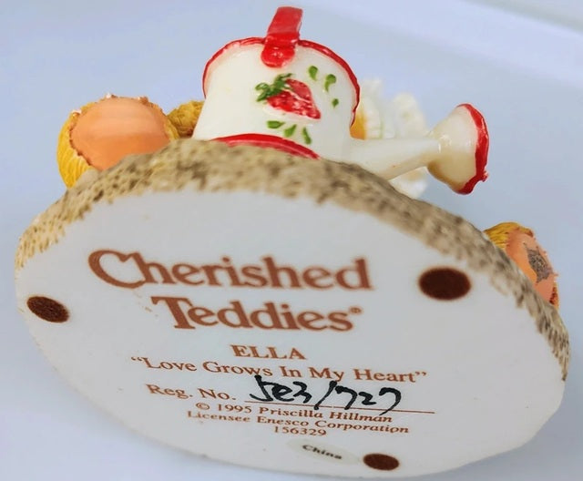 Cherished Teddies Ella figurine with a strawberry on top, featuring branding and licensing information.