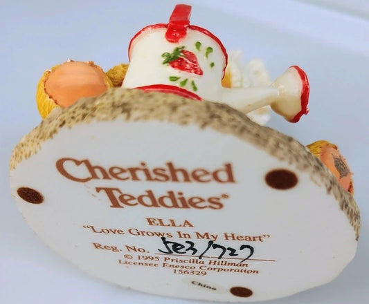 Cherished Teddies Ella figurine with a strawberry on top, featuring branding and licensing information.