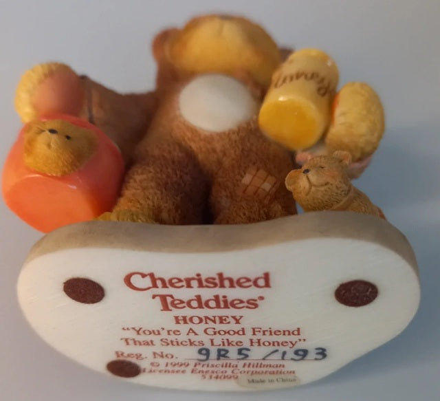 Cherished Teddies Honey bear figurine with a heart-shaped base on a light blue background