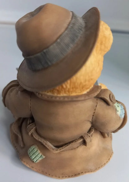 Teddy bear wearing a brown coat and hat on a white background