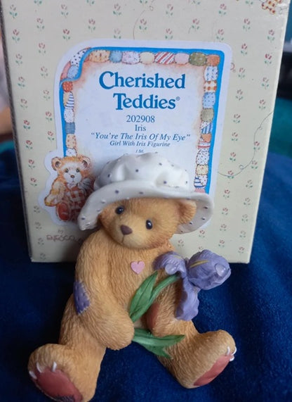 Cherished Teddies bear figurine with a hat and flowers, standing in front of its packaging.
