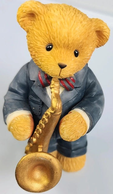 Cherished Teddies Josh teddy bear figurine playing a saxophone on a light gray background