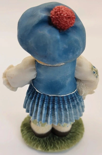 Porcelain figurine of a character with a blue dress and hat on a white background
