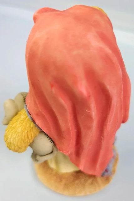 Figurine with a red hood and yellow object on a white background