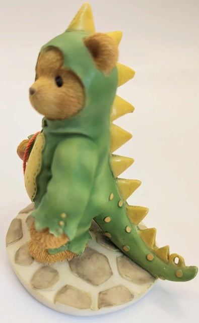 Teddy bear in a green dinosaur costume on a white background