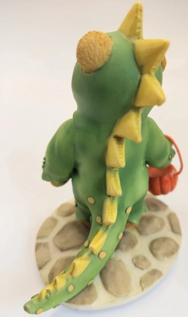 Green dinosaur figurine with yellow spikes on a stone base