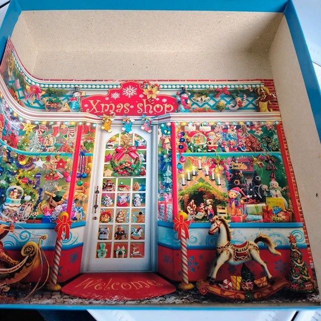 Colorful Christmas-themed diorama with a 'Xmas shop' sign and various decorations.