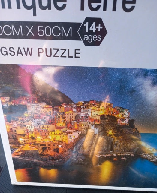 Jigsaw puzzle packaging with a scenic village at night on the cover