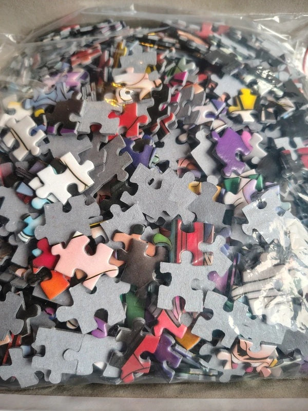 A clear plastic bag filled with many jigsaw puzzle pieces in assorted colors and shapes, photographed close up.