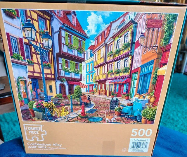 Jigsaw puzzle box with a colorful cobblestone street scene on the cover