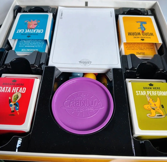 Card game components including cards and a purple lid with 'Carnivium' branding.