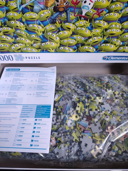 A Clementon 1000-piece jigsaw puzzle featuring a dense pattern of green Toy Story aliens, shown with its instruction sheet and a bag of loose puzzle pieces in a clear plastic bag.