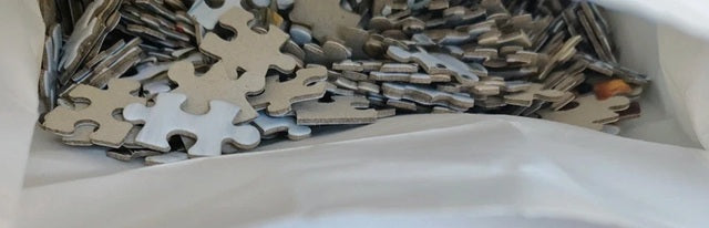 Pile of puzzle pieces with a focus on metallic and white colors.