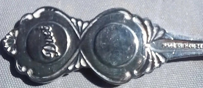 Close-up of a silver spoon with decorative ends on a gray background