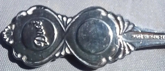 Close-up of a silver spoon with decorative ends on a gray background