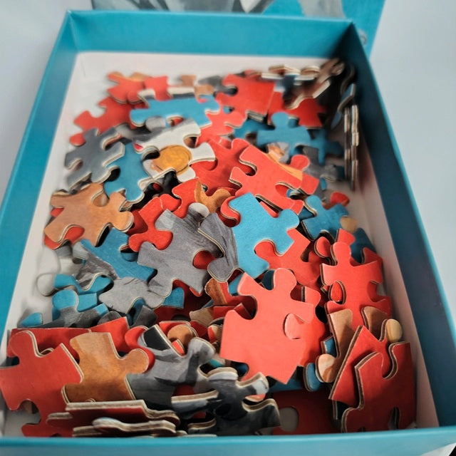 Assorted puzzle pieces in a box with a light blue lid
