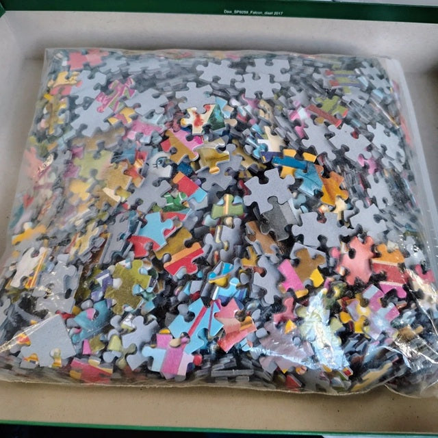 Pile of assorted puzzle pieces in a clear plastic bag on a cardboard surface