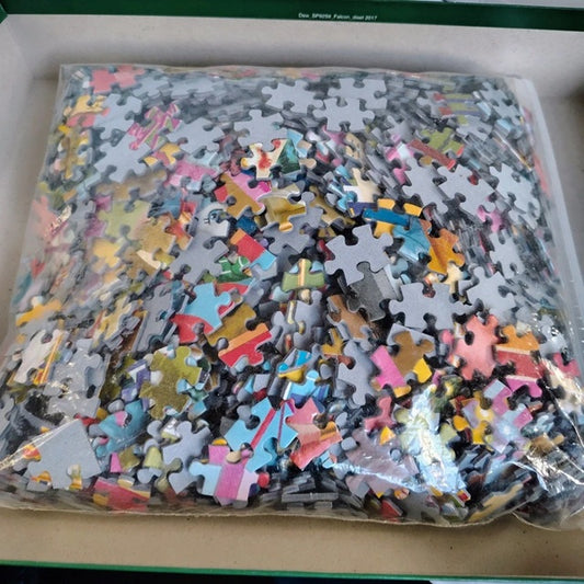 Pile of assorted puzzle pieces in a clear plastic bag on a cardboard surface