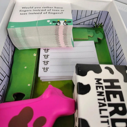 Cartoon cow toy with a book and cards on a green surface