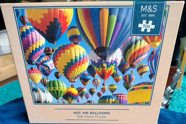 Jigsaw puzzle box with colorful hot air balloons design and M&S branding.