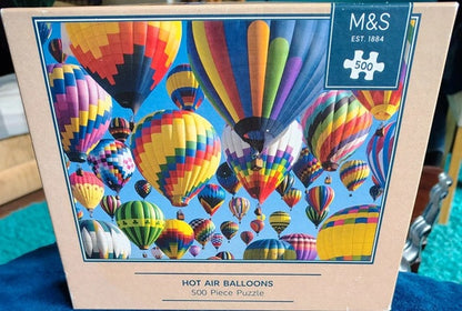 Jigsaw puzzle box with colorful hot air balloons design and M&S branding.