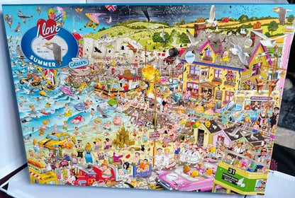 Puzzle box with a colorful summer scene design featuring people, buildings, and activities.
