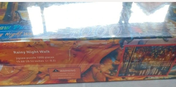 Jigsaw puzzle box titled 'Rainy Night Walk' with colorful design on a reflective surface.
