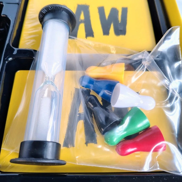 Set of colorful plastic nozzles and a clear sand timer on a yellow background with 'RAW' text.