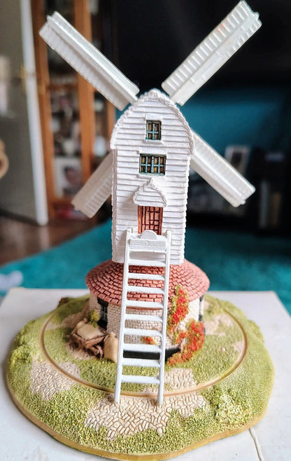 Model of a windmill on a round base with a blurred indoor background