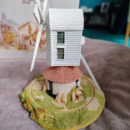Model windmill with a small house on top on a textured surface