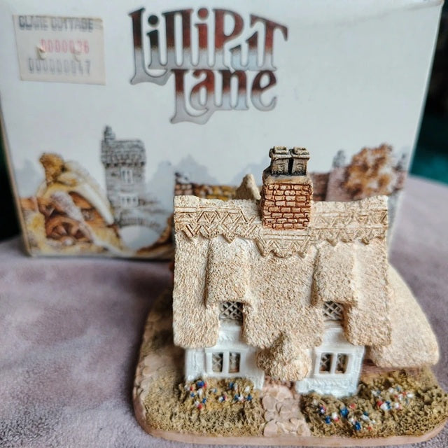 Miniature model of a thatched cottage with 'LiniPat Lane' branding in the background.