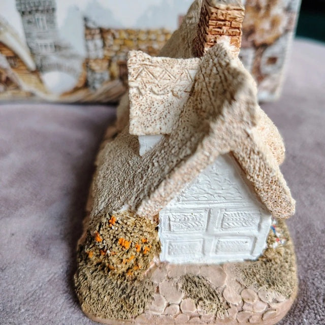 Decorative model of a house with a thatched roof on a textured surface