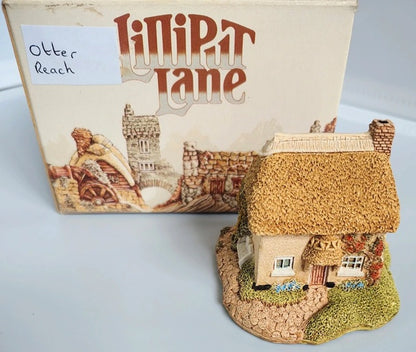 Model of a thatched cottage with 'Lilliput Lane' box in the background. Lilliput Lane Otter Reach.