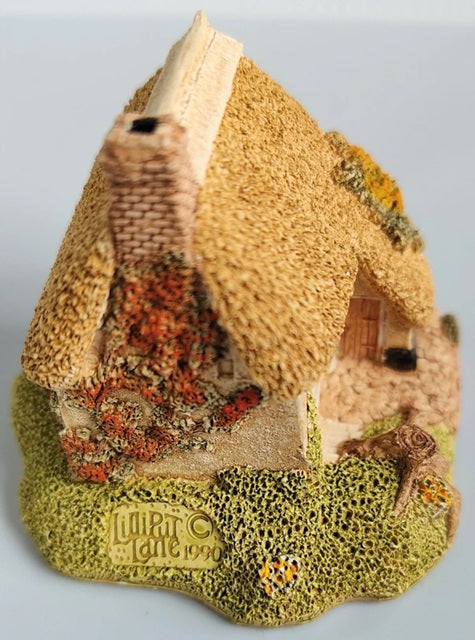 Small model of a thatched cottage with ''Lilliput Lane 1990' branding on a light gray background